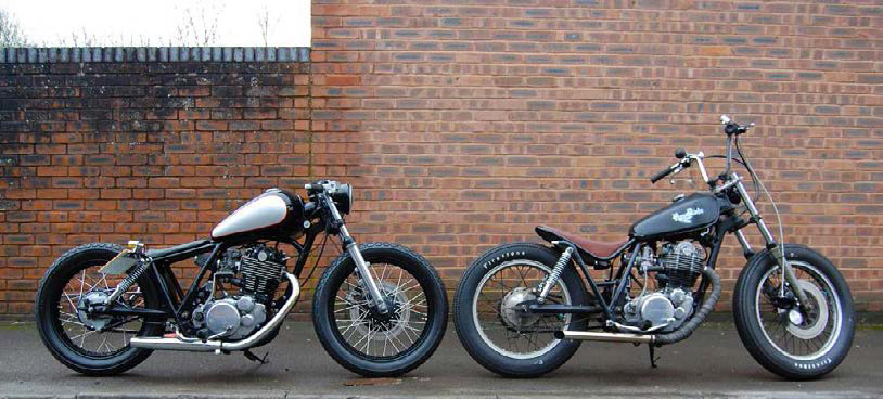 The two different partly finished SR500 customs, from the side, line ahead in front of a brick wall.