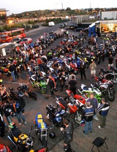 An view from above of a large group of bikes parked outside the Ace, with crowds of bikers and onlookers.