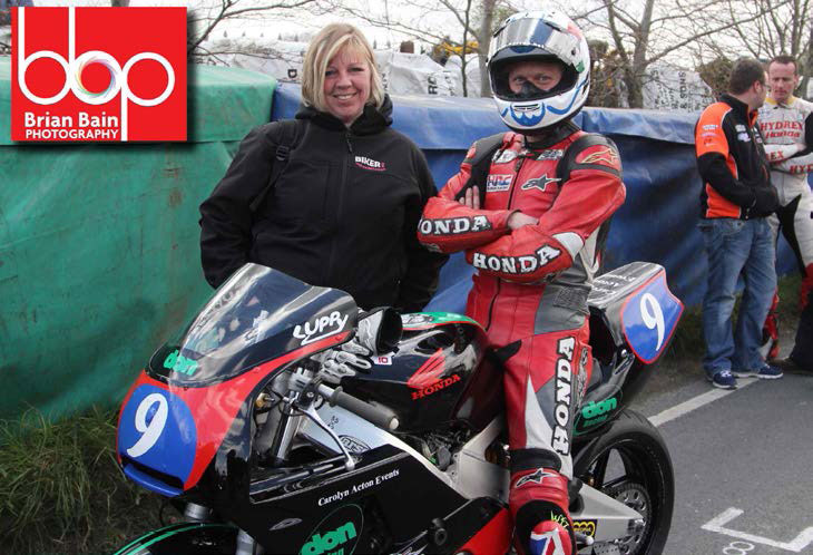 Gail standing next to a motorcycle racer sitting on his bike