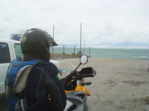 View of the shoulder of a parked biker looking out to sea over a cold beach