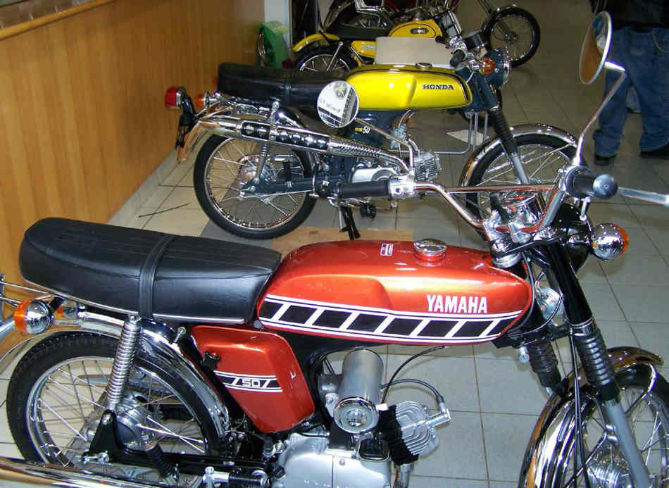 A burgandy FS1-E and a electric green Honda SS50, next to each other, viewed from the side.