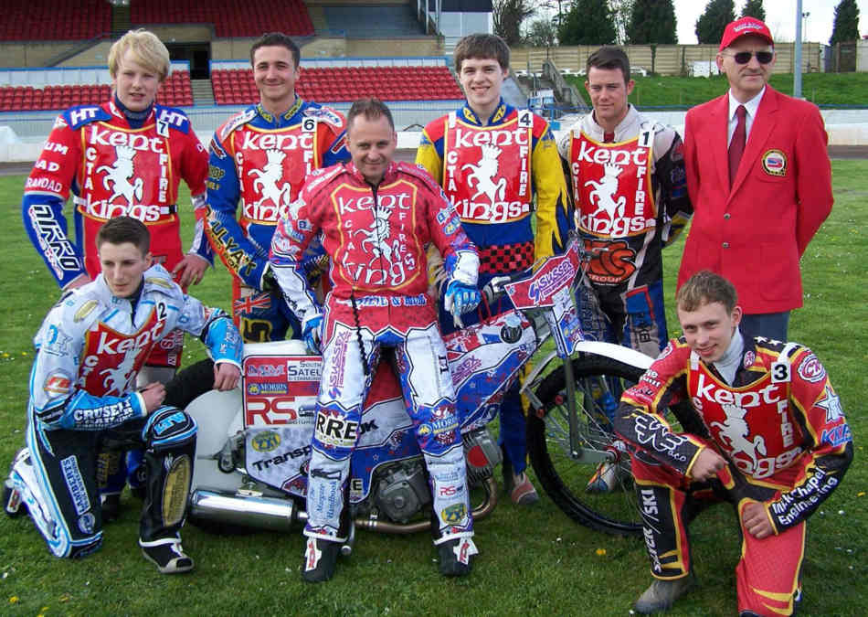 Speedway team standing round and sitting on a bike